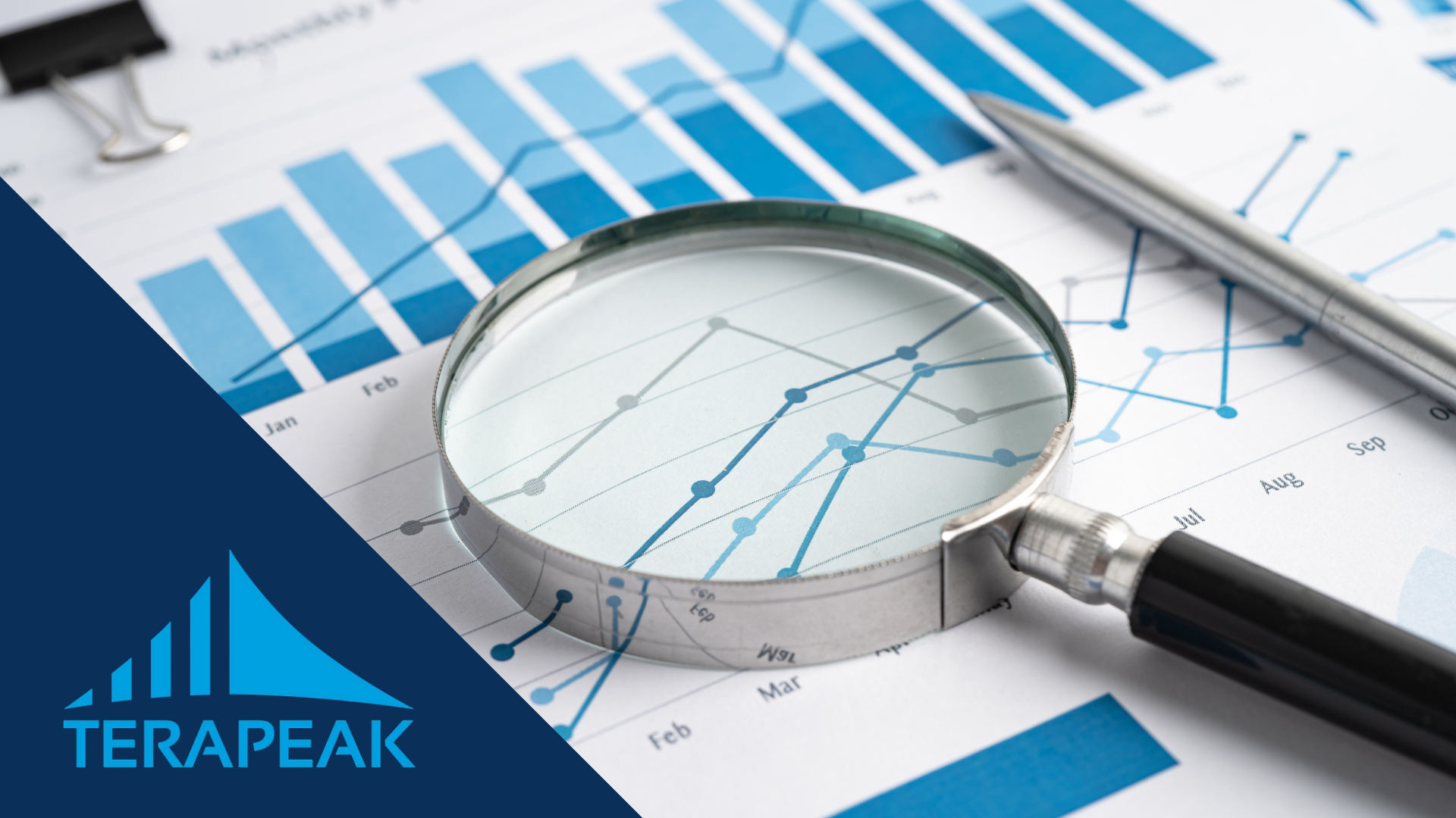 Lupa y bolígrafo sobre gráficos de ventas impresos con el logo de Terapeak, la herramienta para analizar la demanda en eBay